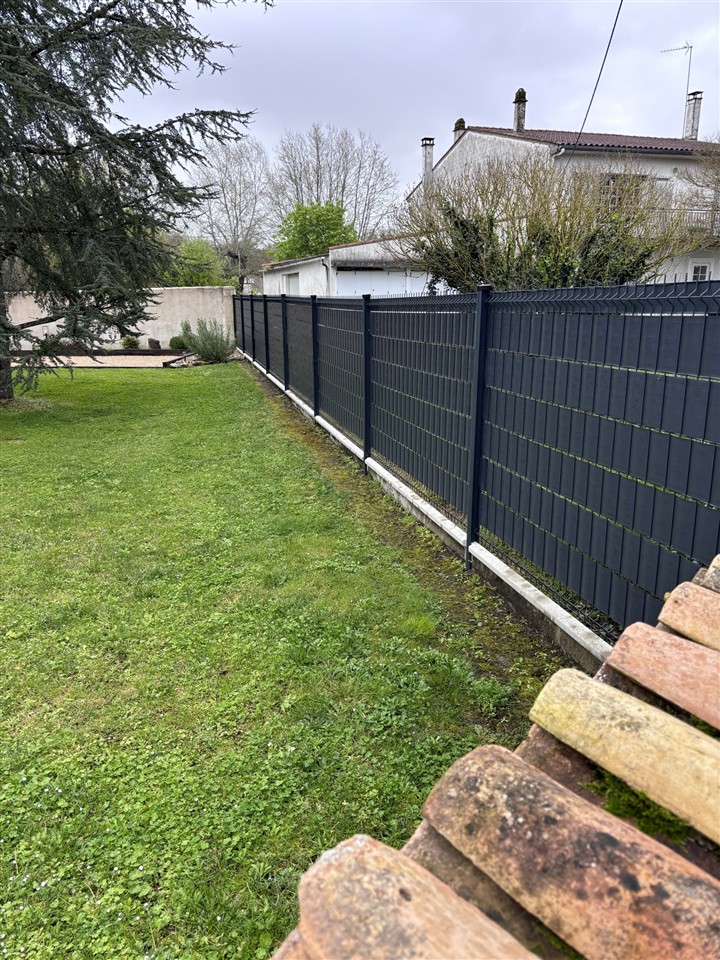 Clôture rigide anthracite avec lames occultantes, posée au bord d'un jardin