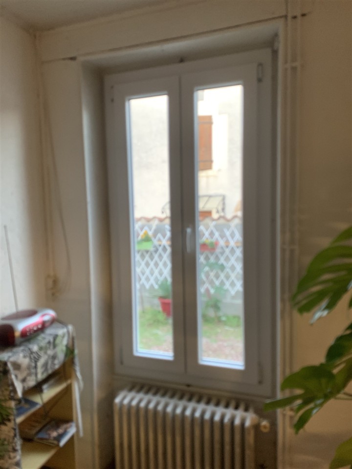 Fenêtre PVC blanche à deux vantaux posée dans une pièce, au-dessus d'un radiateur